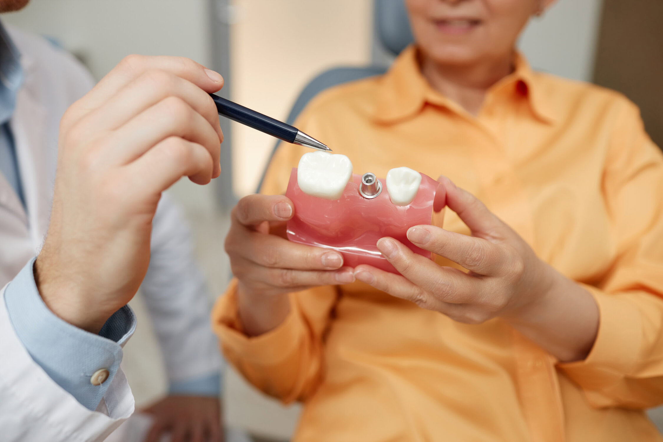 dentist showing dental implants san ramon procedure using tooth model to patient