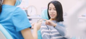 Dental Implants Improve Oral Health A Patient Pointing To A Place With An Implant On An Educational Figure, Asking A Question.