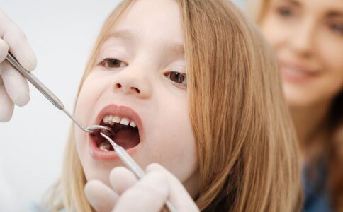 A child getting checked by a dentist with a parent.