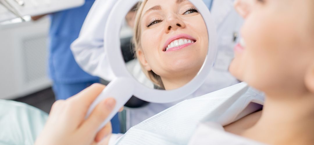 Full Mouth Reconstruction. Woman Looking At Her Smile In Mirror