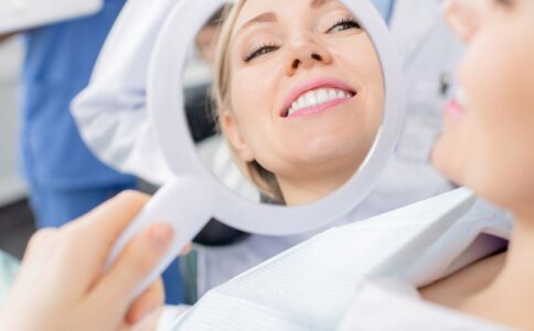 Full Mouth Reconstruction. Woman Looking At Her Smile In Mirror