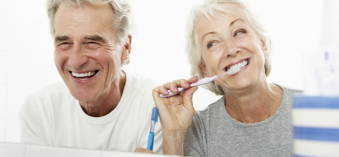A man and woman. The woman is brushing her teeth.