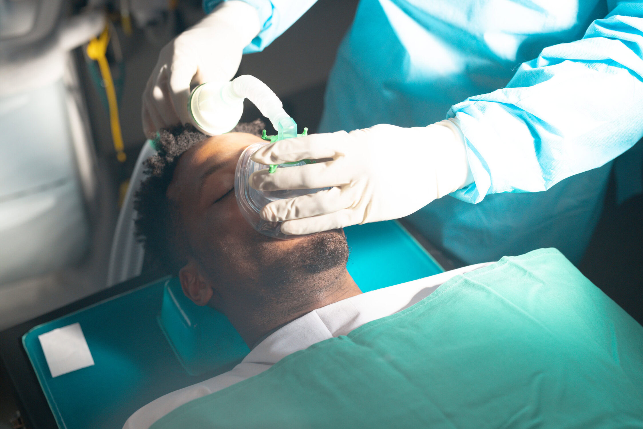 Dentist placing a sedation breathing mask on a patient during a dental procedure at a dental clinic